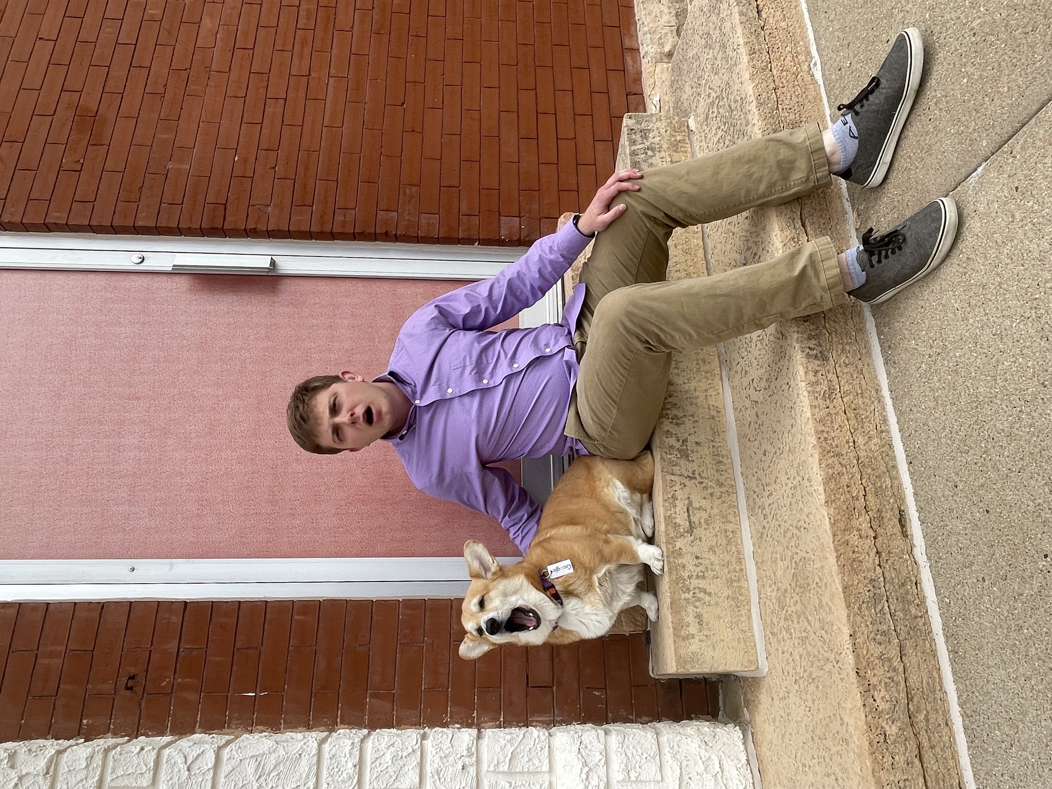 Jala and Cooper sitting on the sidewalk, looking to the side and yawning at the same time.